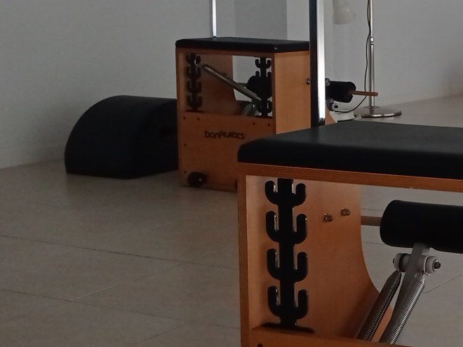 El barril negro apoyado en el suelo, junto a una silla de pilates de madera