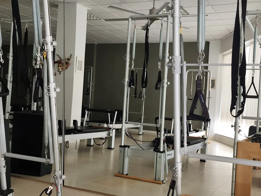 Torres de pilates con sus muelles, correas y barras de empuje, frente al espejo de la sala