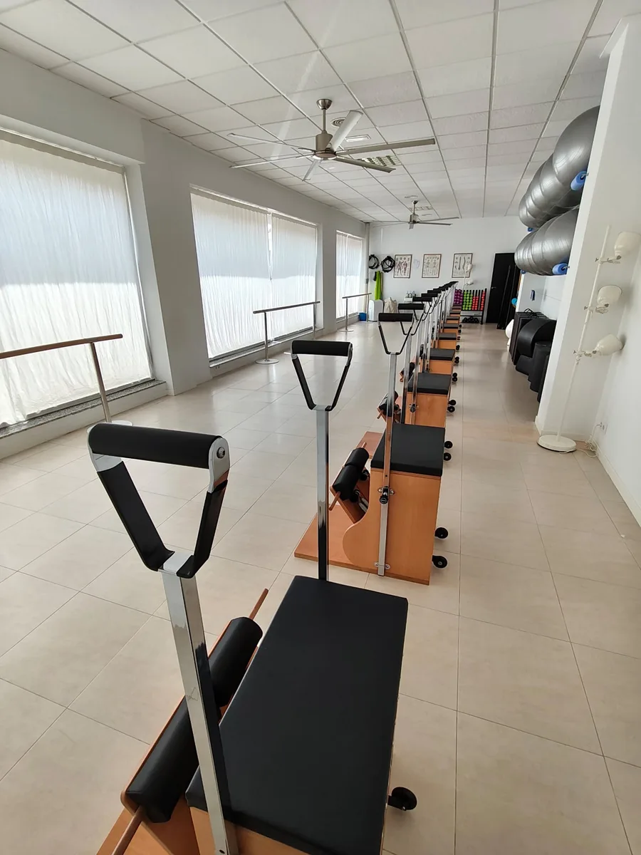 La sala del estudio en perspectiva: la fila de sillas de madera, la barra junto a los ventanales y los fitballs a la derecha