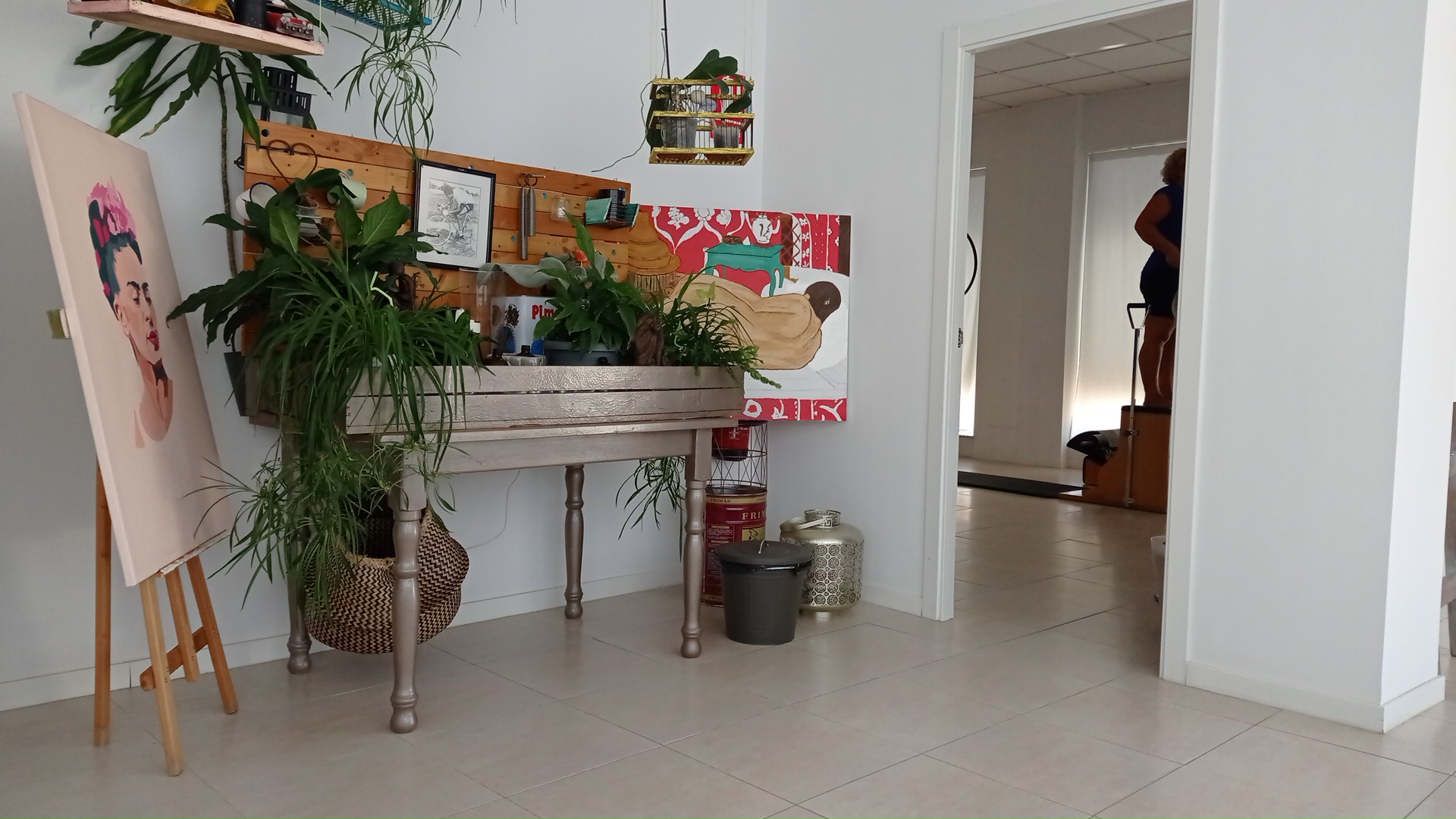 Entrada del estudio con plantas y un cuadro apoyado en un caballete
