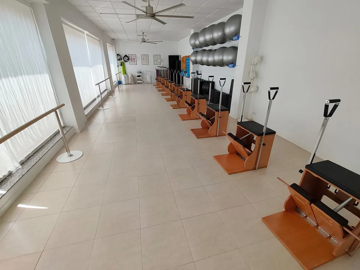 La sala larga con la barra junto a los ventanales de cortina y las sillas alineadas al otro lado